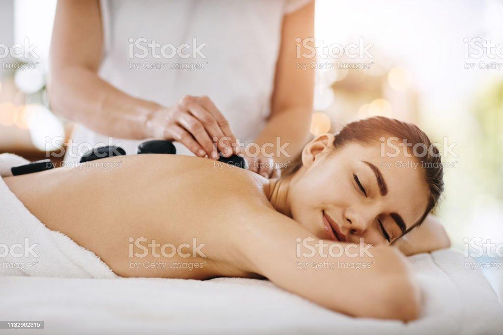 Shot of a young woman getting hot stone therapy at a spa